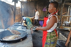 Kenya: Susan Agutu bought an efficient cook stove for her fish restaurant near Lake Victoria from one of the stove builders trained by GIZ in Kenya. She saves potentially 50 per cent of her fuel cost compared to a traditional three stone fire and her guests can enjoy their meals in a smokeless restaurant. <br />
© GIZ / Michael Netzhammer